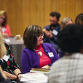 A women smiling in the audience of a panel discussion