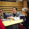 A woman sat at a table talking with fellow conference attendees