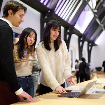 Two women showing a digital business model canvas on a laptop to a man